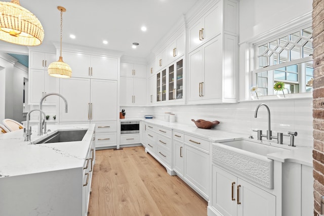 kitchen with pendant lighting, sink, decorative backsplash, light stone counters, and white cabinetry