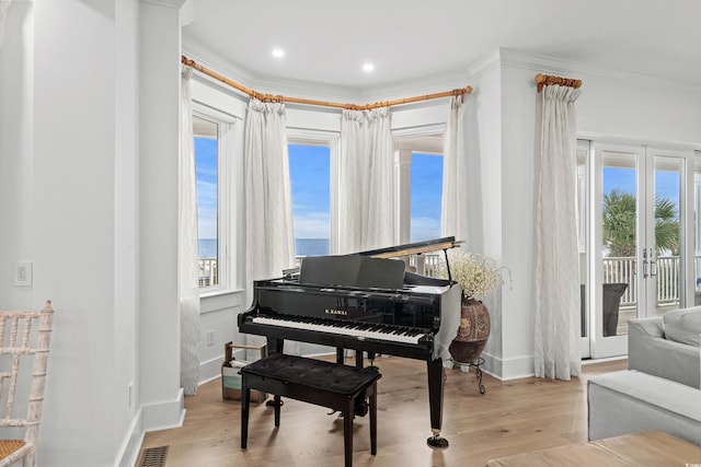 miscellaneous room featuring french doors, light wood-type flooring, a water view, and crown molding