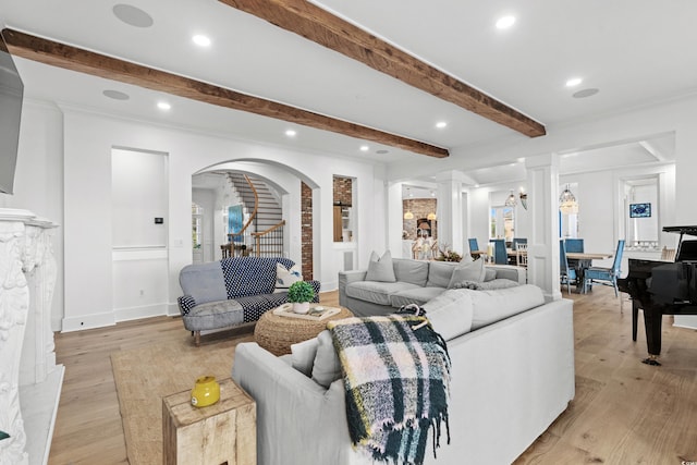 living room featuring decorative columns, crown molding, beamed ceiling, and light hardwood / wood-style floors