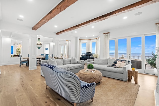 living room featuring beam ceiling, light wood-type flooring, a water view, and an inviting chandelier