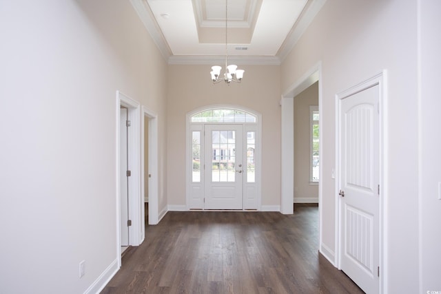 entrance foyer featuring a tray ceiling, dark wood finished floors, ornamental molding, a chandelier, and baseboards