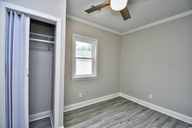 unfurnished bedroom featuring wood-type flooring, a closet, ceiling fan, and ornamental molding