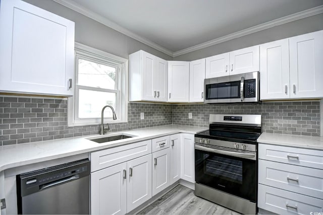 kitchen with tasteful backsplash, white cabinetry, sink, and stainless steel appliances