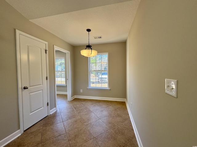 unfurnished dining area with tile patterned flooring and a textured ceiling