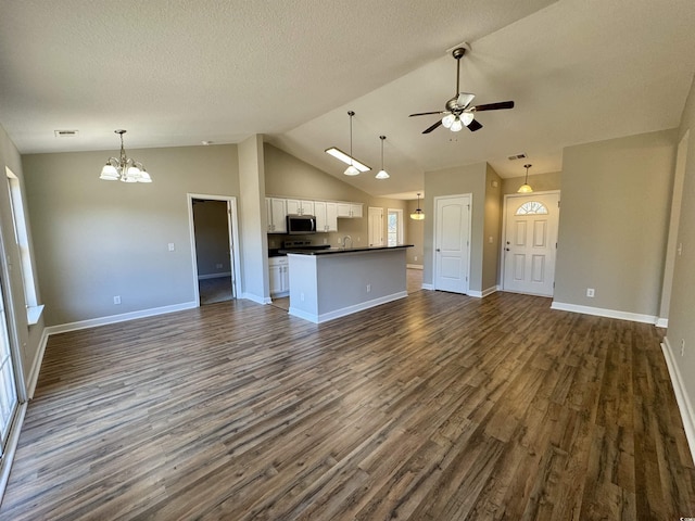 unfurnished living room featuring ceiling fan with notable chandelier, a textured ceiling, dark hardwood / wood-style floors, and lofted ceiling