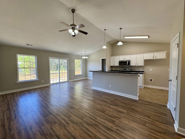 kitchen with lofted ceiling, pendant lighting, dark wood-type flooring, white cabinets, and ceiling fan with notable chandelier