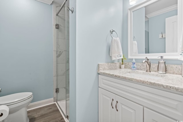 bathroom featuring toilet, a shower with door, wood-type flooring, crown molding, and vanity