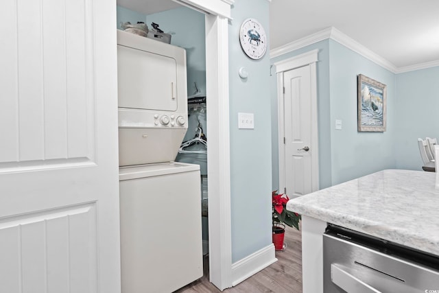 laundry room with crown molding, stacked washer / drying machine, and light hardwood / wood-style flooring