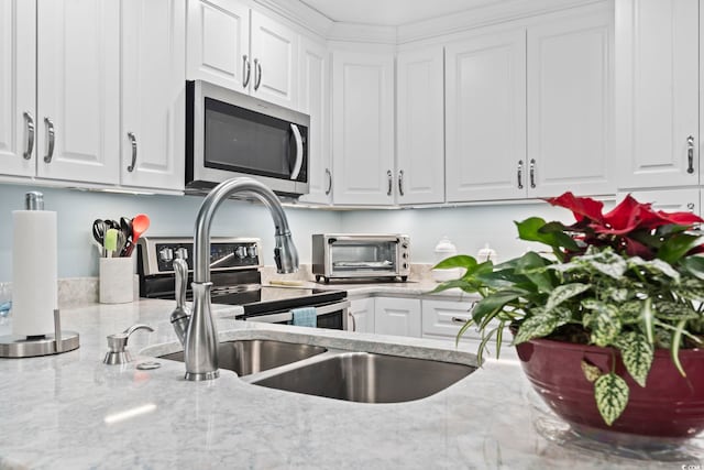 kitchen with white cabinets, light stone countertops, and stainless steel appliances