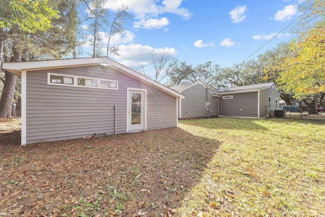 rear view of house with central AC and a yard