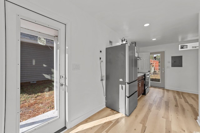 kitchen featuring light countertops, electric range, light wood-style floors, freestanding refrigerator, and electric panel