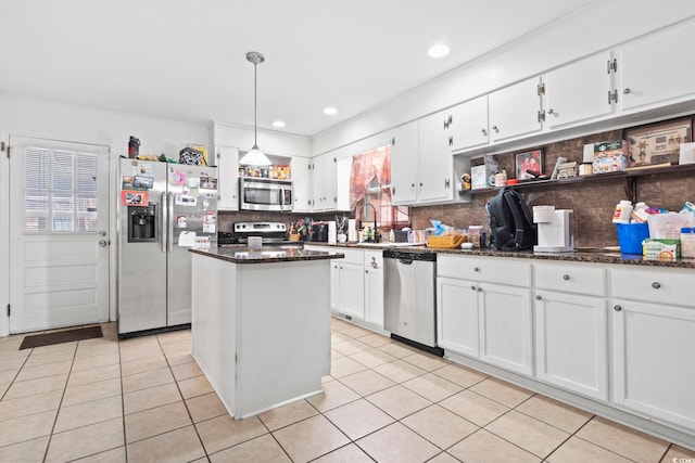 kitchen with appliances with stainless steel finishes, backsplash, white cabinetry, and a kitchen island