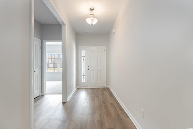 foyer with baseboards, visible vents, and wood finished floors