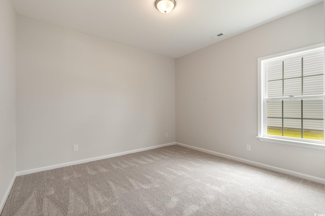 carpeted spare room featuring baseboards and visible vents