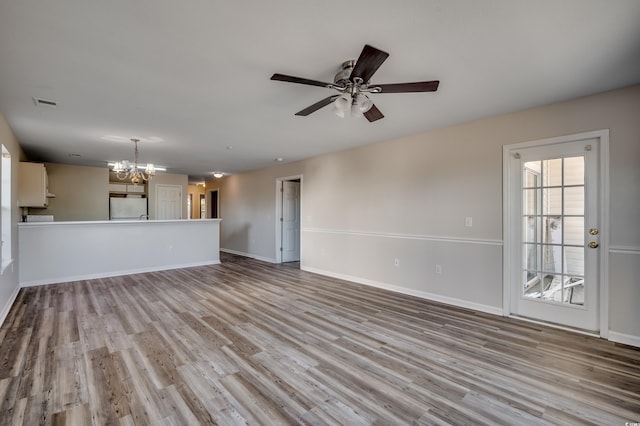 unfurnished living room with ceiling fan with notable chandelier and light hardwood / wood-style floors