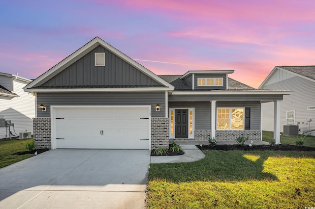 craftsman inspired home with a porch, a garage, a yard, and central air condition unit