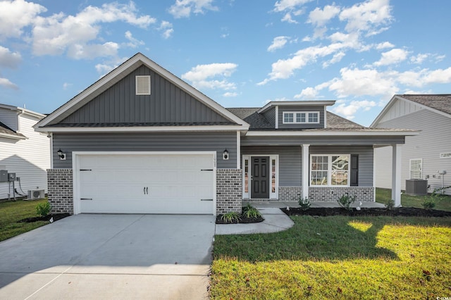 craftsman house with a front yard, central AC unit, a porch, and a garage