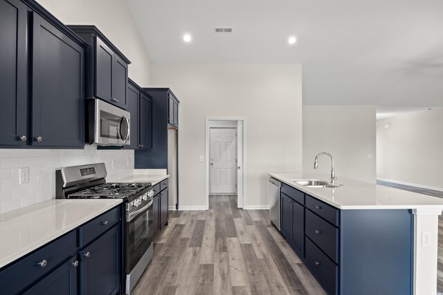 332 Hayloft Cir, Conway, SC 29526 - kitchen with appliances with stainless steel finishes, decorative backsplash, light wood-style flooring, light countertops, and a center island with sink