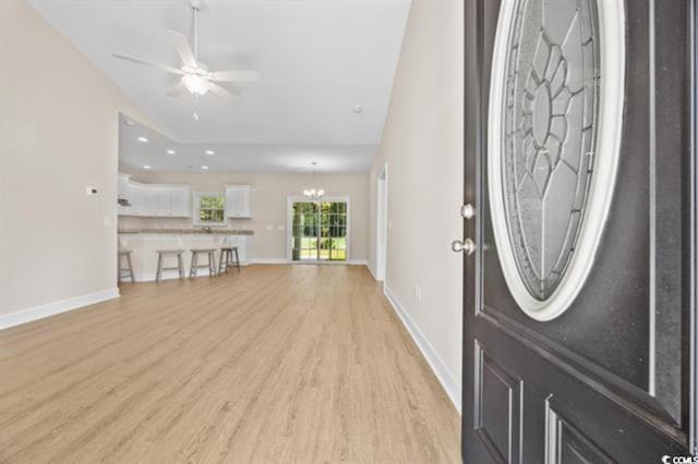 entryway featuring lofted ceiling, ceiling fan with notable chandelier, and light wood-type flooring