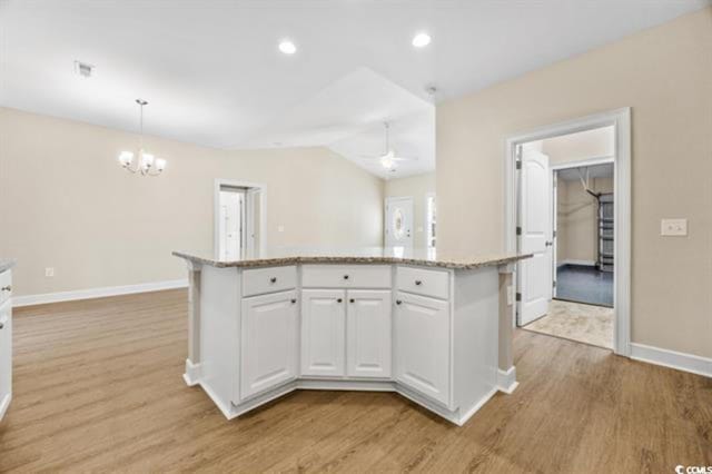 kitchen featuring pendant lighting, white cabinetry, a center island, light hardwood / wood-style floors, and light stone countertops