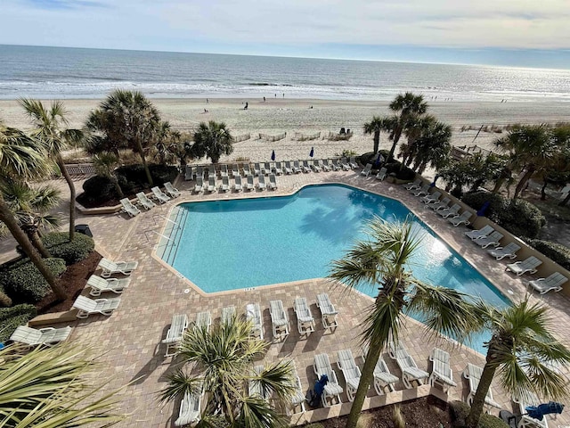 view of swimming pool with a beach view and a water view