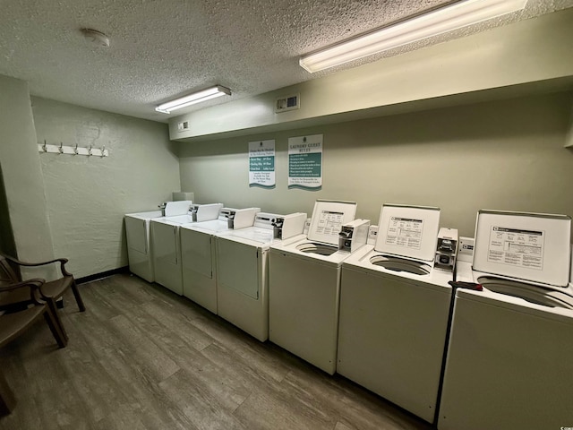 washroom with dark hardwood / wood-style flooring, separate washer and dryer, and a textured ceiling