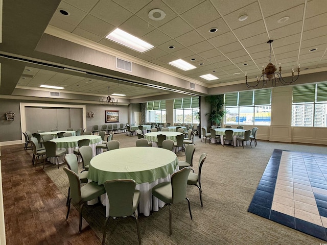 carpeted dining space with a paneled ceiling and crown molding