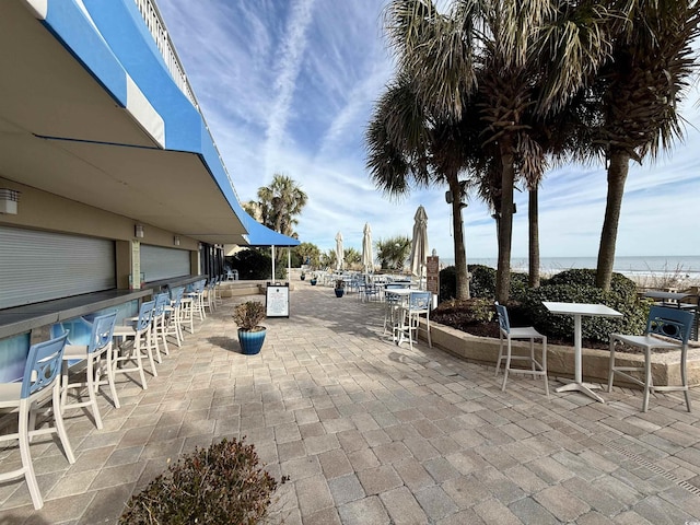 view of patio featuring a water view and exterior bar