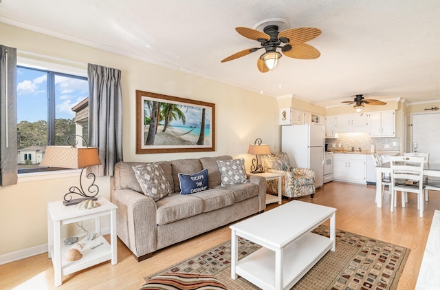 living room with crown molding, ceiling fan, and light hardwood / wood-style floors