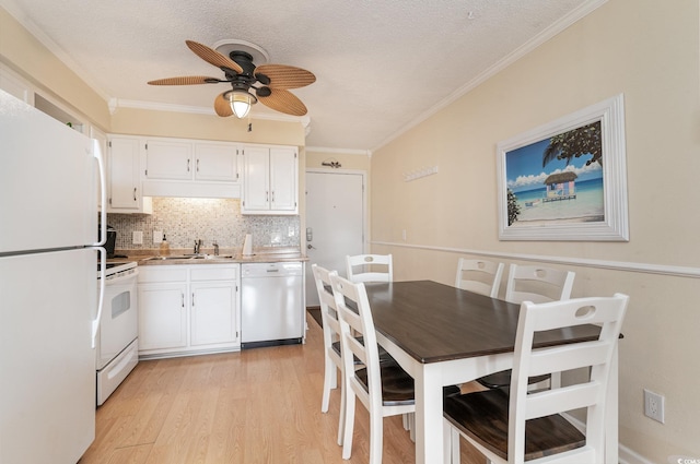 kitchen with light wood-type flooring, backsplash, white appliances, sink, and white cabinets