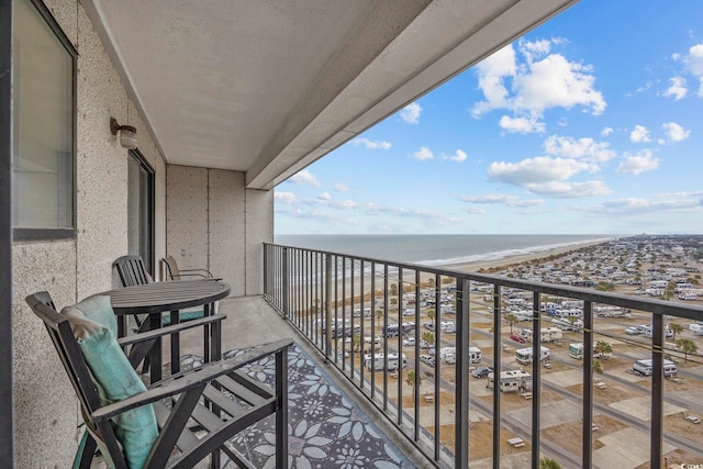 balcony with a water view and a view of the beach