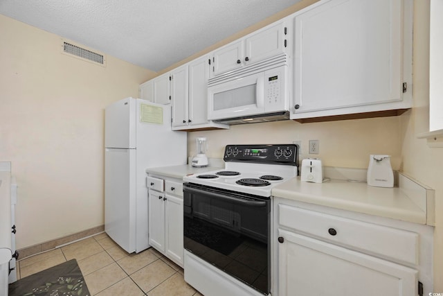 kitchen with a textured ceiling, white cabinetry, light tile patterned floors, and white appliances