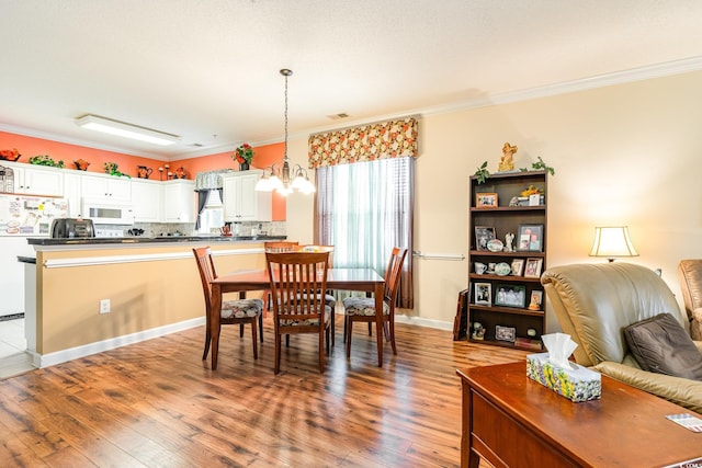 dining area featuring hardwood / wood-style floors, crown molding, and a notable chandelier