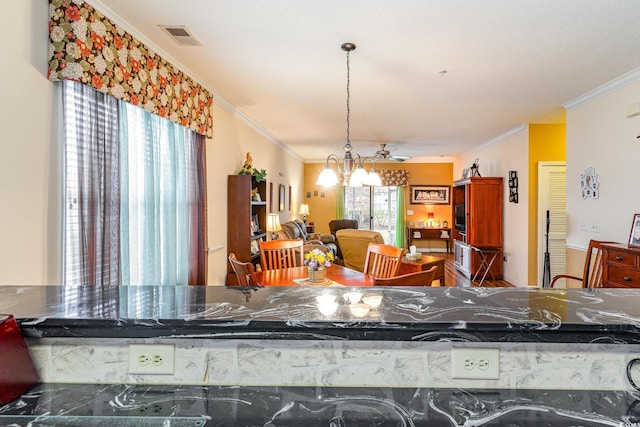 kitchen featuring an inviting chandelier, ornamental molding, a healthy amount of sunlight, and hanging light fixtures