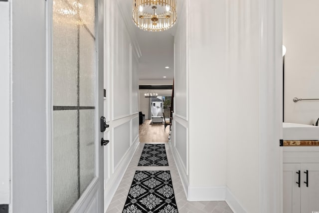 corridor with crown molding, sink, tile patterned flooring, and a notable chandelier