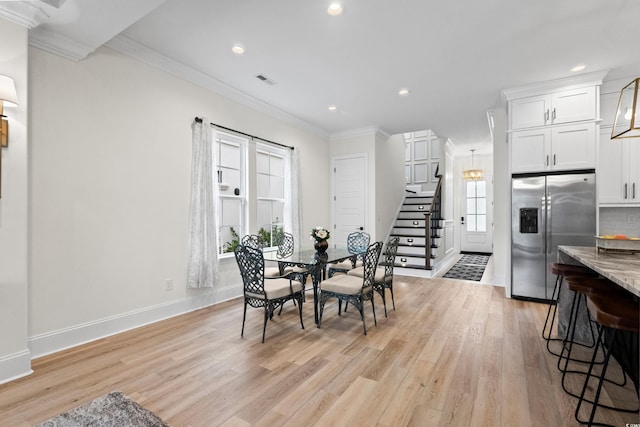 dining area with crown molding and light wood-type flooring