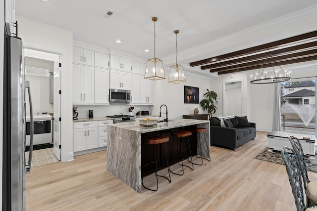 kitchen featuring pendant lighting, light stone countertops, an island with sink, appliances with stainless steel finishes, and white cabinetry