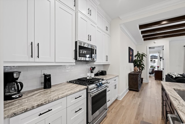 kitchen with appliances with stainless steel finishes, tasteful backsplash, beam ceiling, light stone counters, and white cabinetry