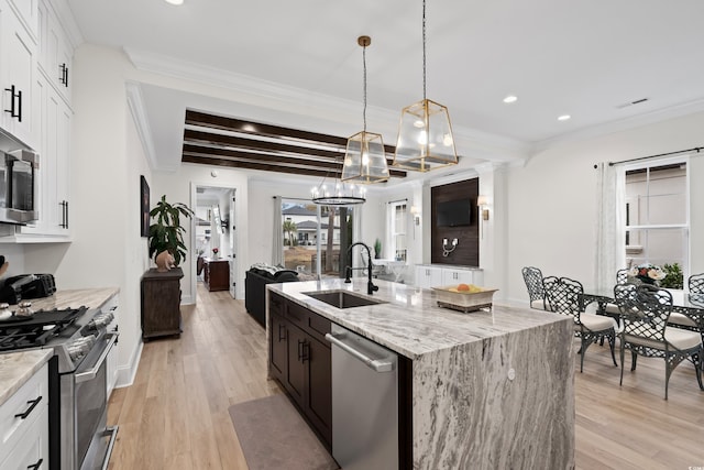 kitchen featuring sink, light stone countertops, an island with sink, appliances with stainless steel finishes, and white cabinetry