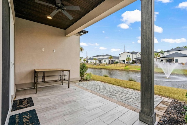 view of patio with a water view and ceiling fan