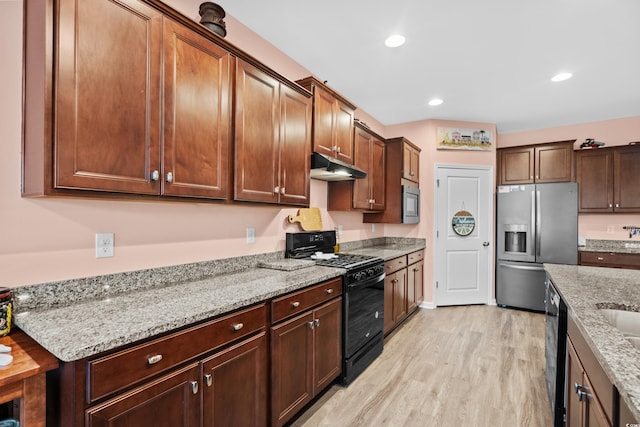 kitchen featuring black appliances, light hardwood / wood-style floors, and light stone counters