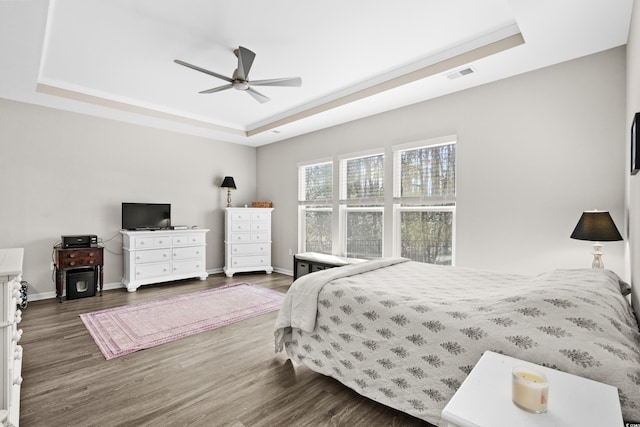 bedroom with a raised ceiling, ceiling fan, and dark wood-type flooring