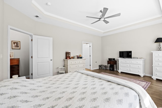 bedroom with ceiling fan, dark hardwood / wood-style flooring, a raised ceiling, and ornamental molding