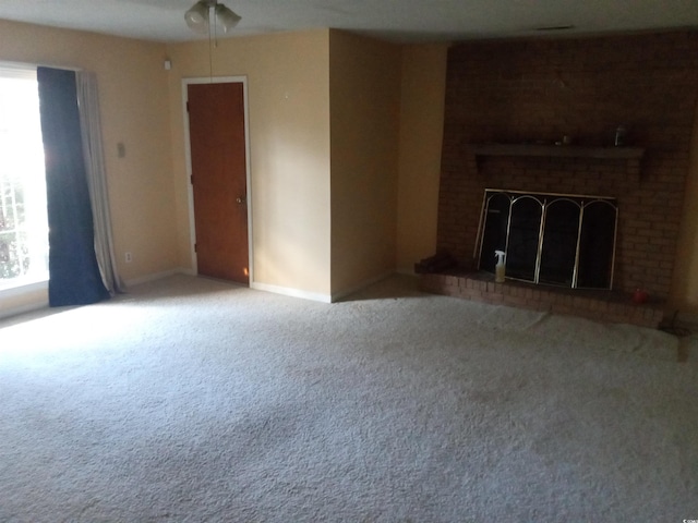 unfurnished living room with carpet floors, a brick fireplace, and ceiling fan