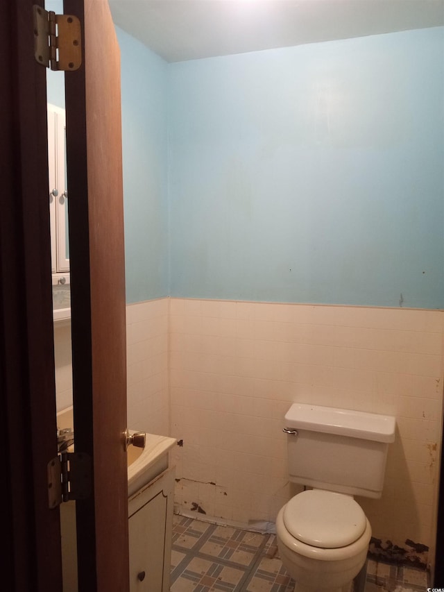 bathroom with vanity, toilet, and tile walls