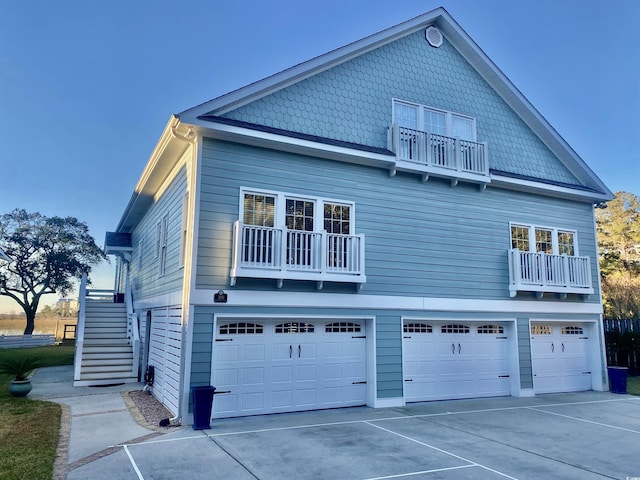 view of side of home with a balcony, concrete driveway, and an attached garage