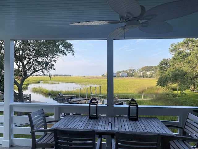 wooden deck featuring a rural view, outdoor dining area, ceiling fan, and a water view