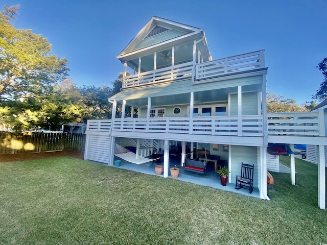 back of property featuring a lawn, a ceiling fan, fence, a balcony, and a patio area