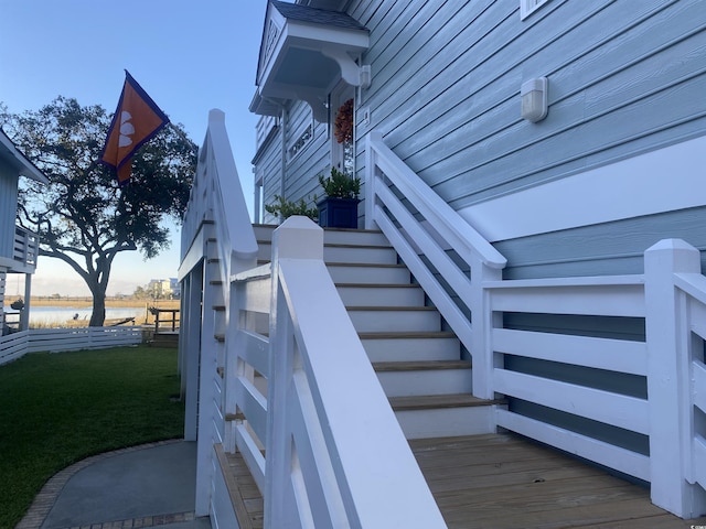 view of side of home featuring a lawn, stairs, and a water view