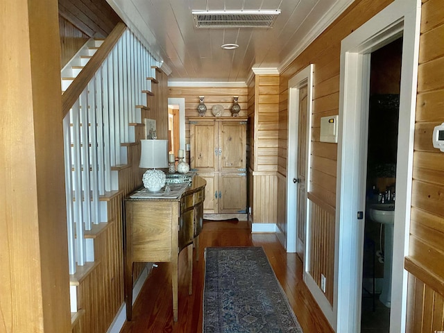 hallway featuring crown molding, dark hardwood / wood-style floors, and wooden walls